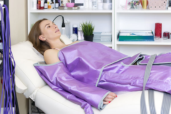 femme avec coussins de pressotherapie sur les bras et jambes